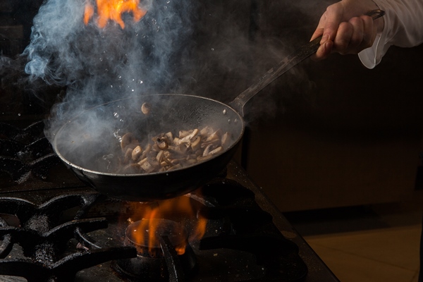 side view mushroom frying with smoke and fire and human hand and pan in stove - Пирог из гречневой каши с грибами