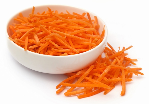 sliced carrot in a bowl over white background - Постная тушёная морковь с черносливом и мёдом