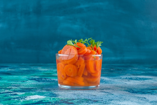 sliced carrots in a glass on the blue table - Капуста белокочанная для быстрого употребления