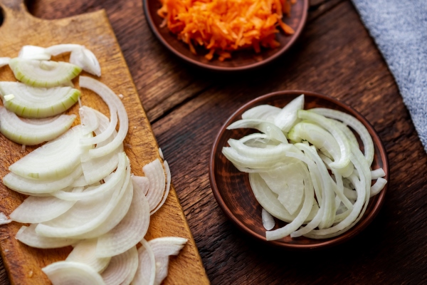 sliced onions and carrots on a dark wooden background ingredients preparation for cooking - Капуста тушёная