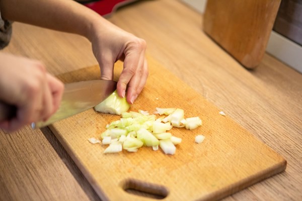 slicing onion on cut board - Подливка овощная постная