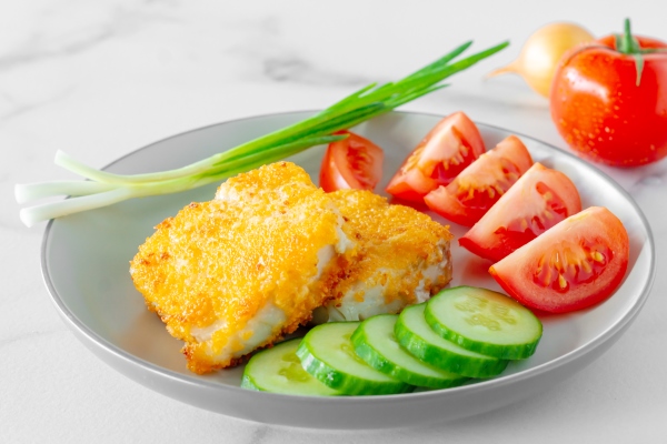 tasty roasted fish fillet in breadcrumbs and fresh vegetables on a plate healthy dinner - Рыба жареная или печёная