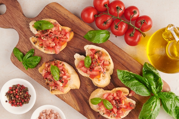 tasty savory tomato italian appetizers or bruschetta on slices of toasted baguette garnished with basil vegetables herbs on grilled or toasted crusty ciabatta bread - Постный перекус на хлебе