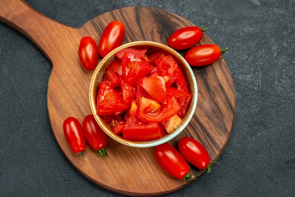 top close view of tomatoes on plate stand on dark grey background - Постные фаршированные сладкие перцы