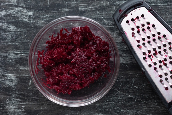top view of grated cooked beet in glass bowl and grater - Свекольный салат