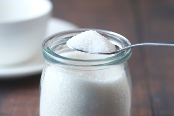 white sugar and spoon in a container on black background - Кисель из сушёной черники