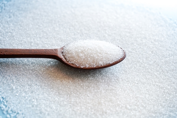white sugar in wooden spoon on sugar background with selective focus - Маседуан из вишен и груш