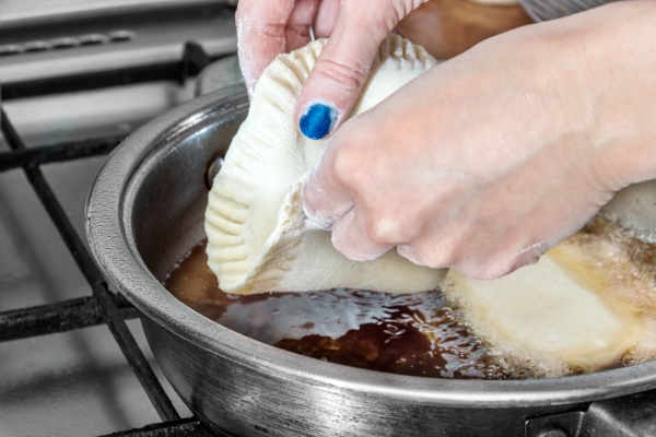 woman fries chebureki in a pan with vegetable oil - Чебуреки постные