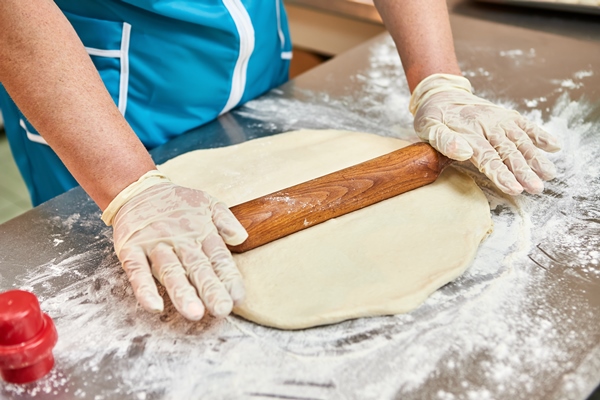 women chef hands rolls out dough with rolling pin for cooking dumplings ravioli or khinkali - Вареники с капустой