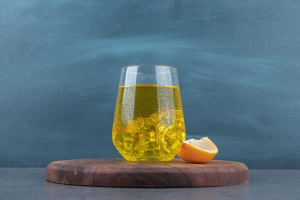 a glass cup of lemonade with ice cubes and sliced lemon - Квас царский