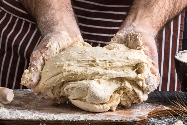 a handful of flour with egg on a rustic kitchen against the background of men s hands knead the dough ingredients for cooking flour products or dough bread muffins pie pizza dough copy space - Домашние городские булки