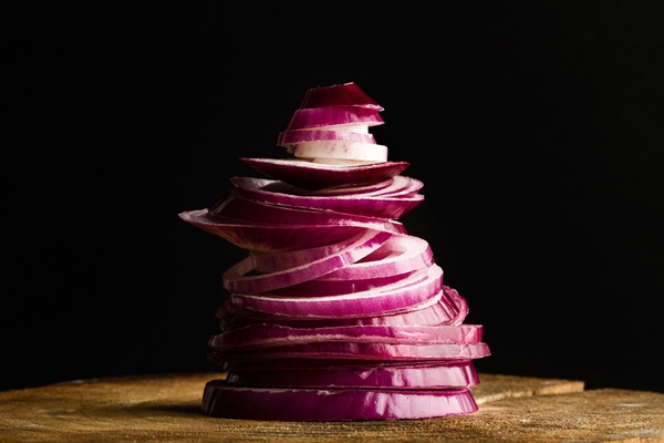 a heap of sliced purple onion on a wooden table on a dark background - Гороховый суп с кабачками