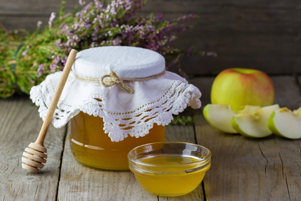 a jar of honey with a stick and a bowl on the table - Тверской квас