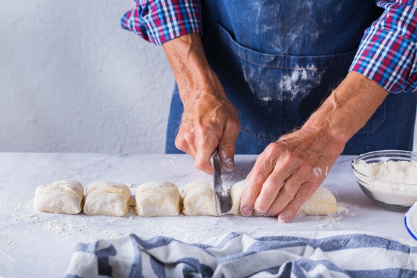 baking eating at home healthy food and lifestyle concept senior baker man cooking kneading fresh dough with hands rolling with pin spreading the filling on the pie on a kitchen table with flour 4 - Французский багет