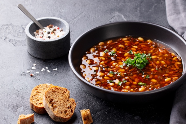 bean soup in a black bowl black background copy space - Постный суп с орехами