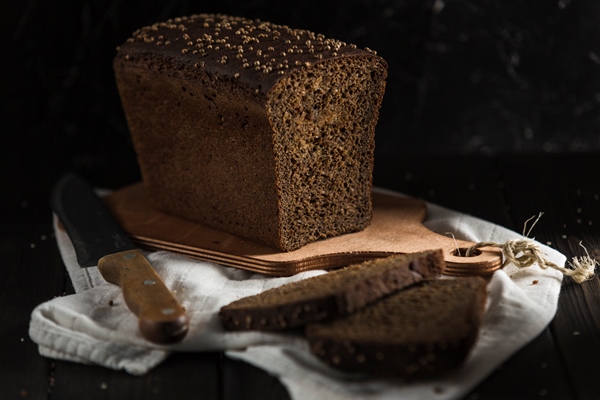 black bread with caraway seeds slices lay on a wooden board - Квас тминный