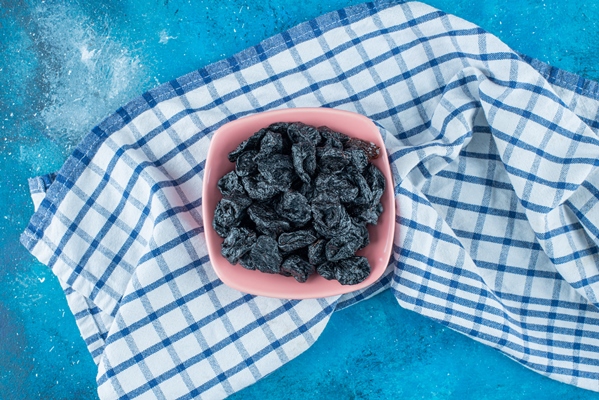 black raisins in a bowl on tea towel on the blue table - Филёвский квас