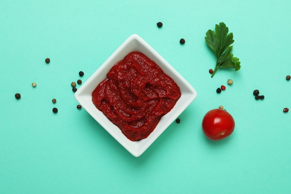 bowl of tomato paste peppercorns parsley and tomato on mint surface - Солянка овощная