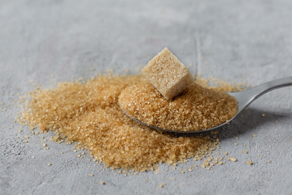 brown cane sugar crystals and cube of refined sugar in a spoon on grey table - Квас из сухого хлебного кваса с мятой