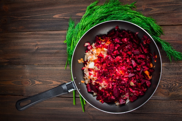 carrots beets and onions in a frying pan around dill on a brown wooden background - Борщ свекольный с перловой крупой