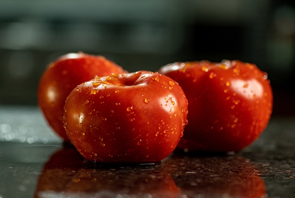 closeup of fresh ripe tomatoes with water droplets on a black granite kitchen counter surface - Суп-пюре из помидоров с перловой крупой