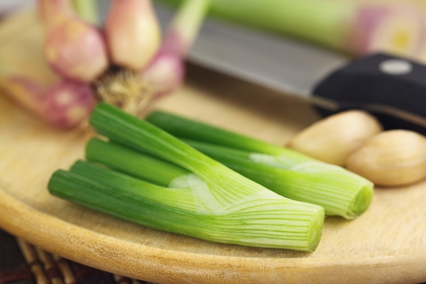 closeup of sliced onion leaves with onion and knife - Суп с картофелем по-румынски