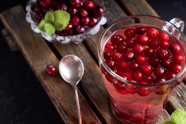 cranberry juice with honey in a cup cranberries in sugar on a dark wooden table - Клюквенный квас с можжевеловыми ягодами