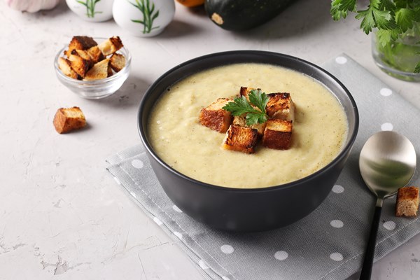 creamy chicken and zucchini thick soup served with white bread croutons in dark bowl on gray background close up - Суп-пюре из яблок острый