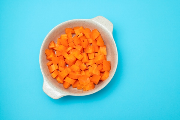 cut cubes of fresh carrot in the bowl on blue - Щи по-крестьянски
