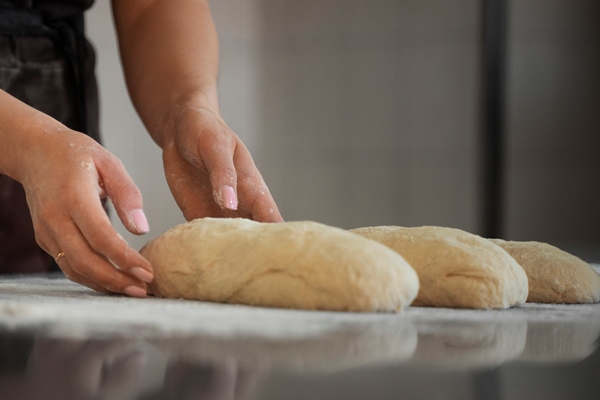 female baker handling bread dough in the pastry shop - Бездрожжевой гречневый хлеб