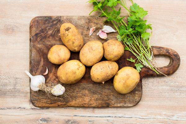flat lay raw potatoes on wooden board - Драники с кабачками и манкой