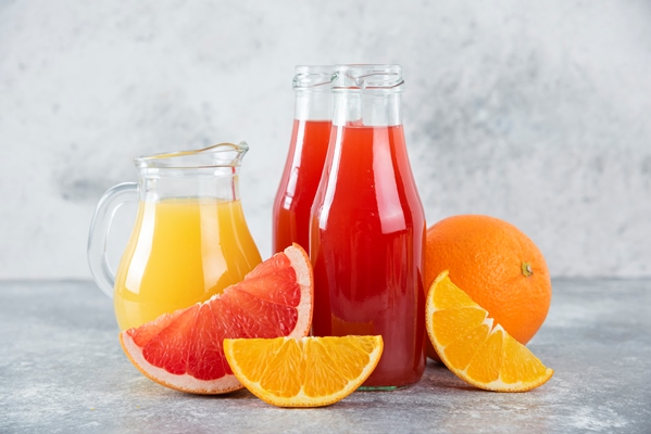glass pitchers of grapefruit juice with slices of orange fruits - Квас плодово-ягодный