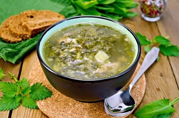 green soup of sorrel nettle and spinach in a bowl spoon bread pepper against a wooden board - Щи зелёные из молодой крапивы