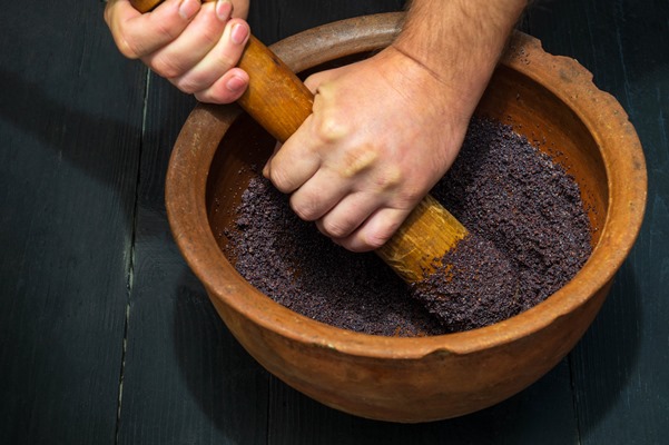 grinding poppy seeds in an old clay pot for making kutya or pies the national dish is prepared before any holiday - Коливо из пшеницы