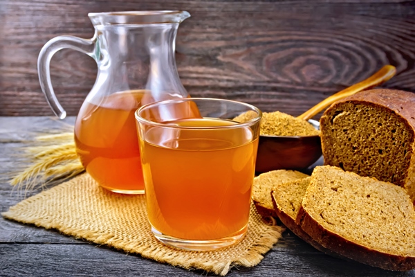 kvass in glassful and glass jug on burlap malt in a bowl rye bread on wooden plank background - Свекольник постный