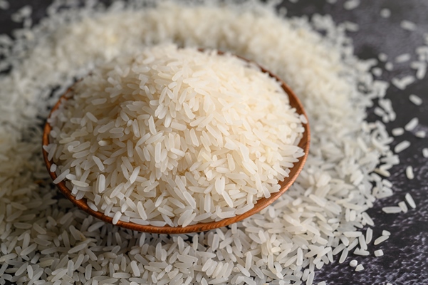 milled rice in a bowl and a wooden spoon on the black cement floor 1 - Суп из листьев лопуха с рисом и картофелем