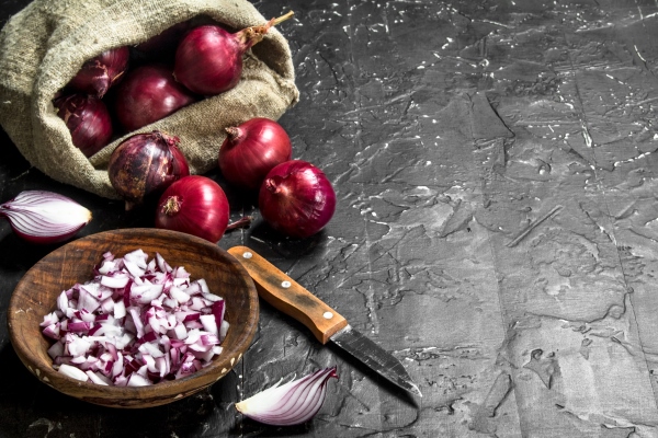pieces of onions in a bowl and onions in the sack with a knife on black rustic background - Суп вермишелевый