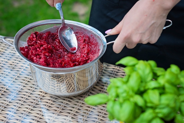 professional cook hands prepares cranberry berry puree by rubbing berries through a sieve the process of making marmalade - Воскресный квас