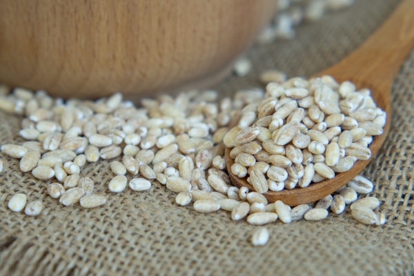 raw pearl barley in a wooden spoon spilling on an old wooden table - Суп перловый с репой