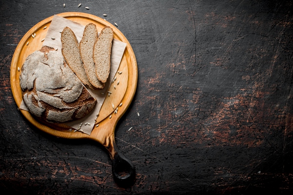 rye bread on a round cutting board on dark rustic background - Квас с черносмородиновыми листьями