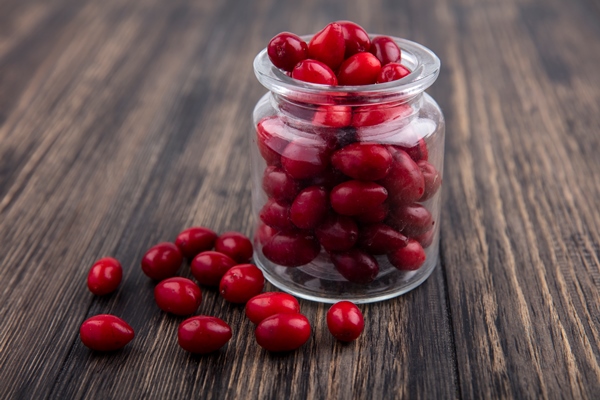 side view of cornel berries in jar and on wooden background - Московский квас