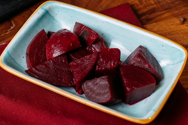 side view of slices of cooked beet in a plate on a wooden table - Ботвинья «Весна»