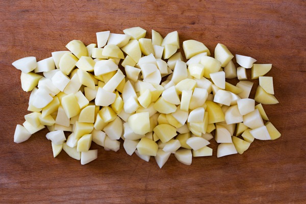 sliced raw potatoes on a old cutting board - Суп картофельный с бобовыми