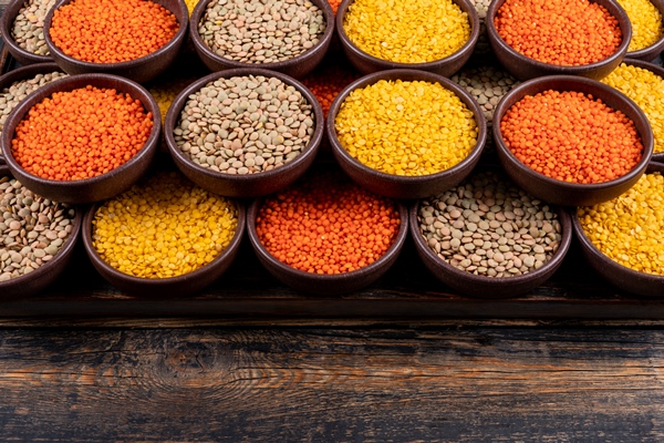 some of yellow green and red lentils in a brown bowls on dark wooden table high angle view - Суп чечевичный