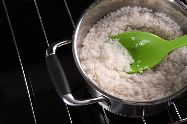 spoon with rice in metal pan on hotplate - Суп рисовый с овощами