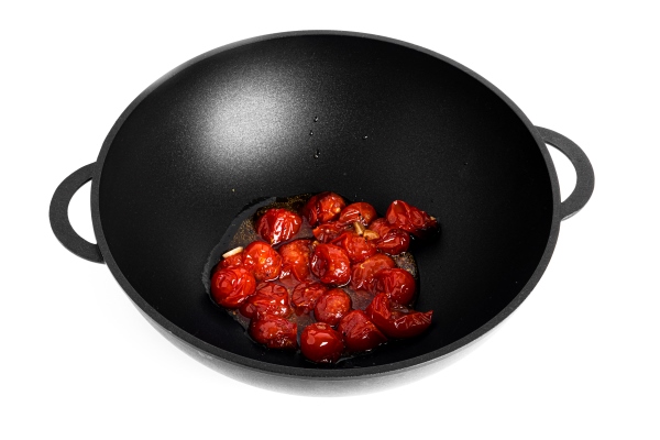 stewed cherry tomatoes with garlic in a wok pan isolated on a white background preparation of bucatini pasta high quality photo - Томатный постный cуп
