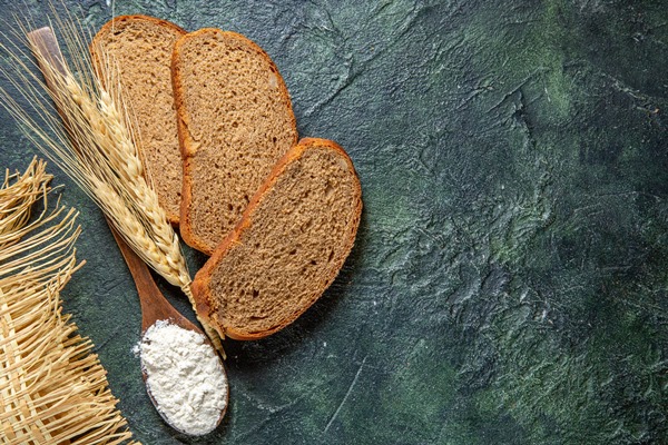 top view flour on wooden spoon with dark bread loafs on dark desk - Квас суточный с лимоном