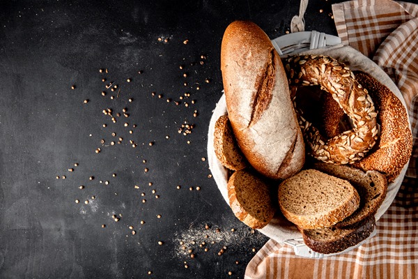 top view of basket full of breads as baguette bagel rye with sunflower seeds on black surface - Черничный суп