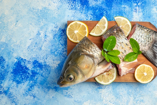 top view sliced fresh fish with lemon slices on blue surface - Солянка рыбная сборная