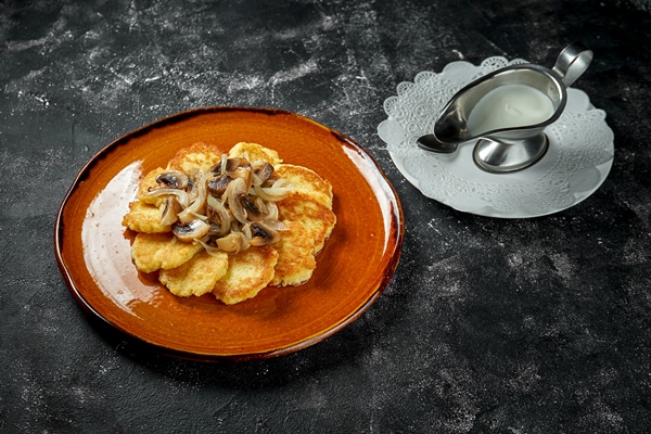 traditional potato pancakes with forest mushrooms and sour cream on a dark table raggmunk draniki deruny - Драники с кабачками и манкой